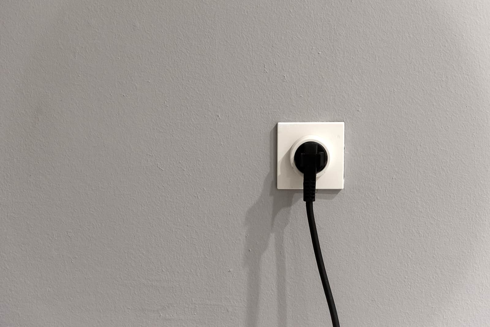 A plug in a wall outlet against a plain white wall