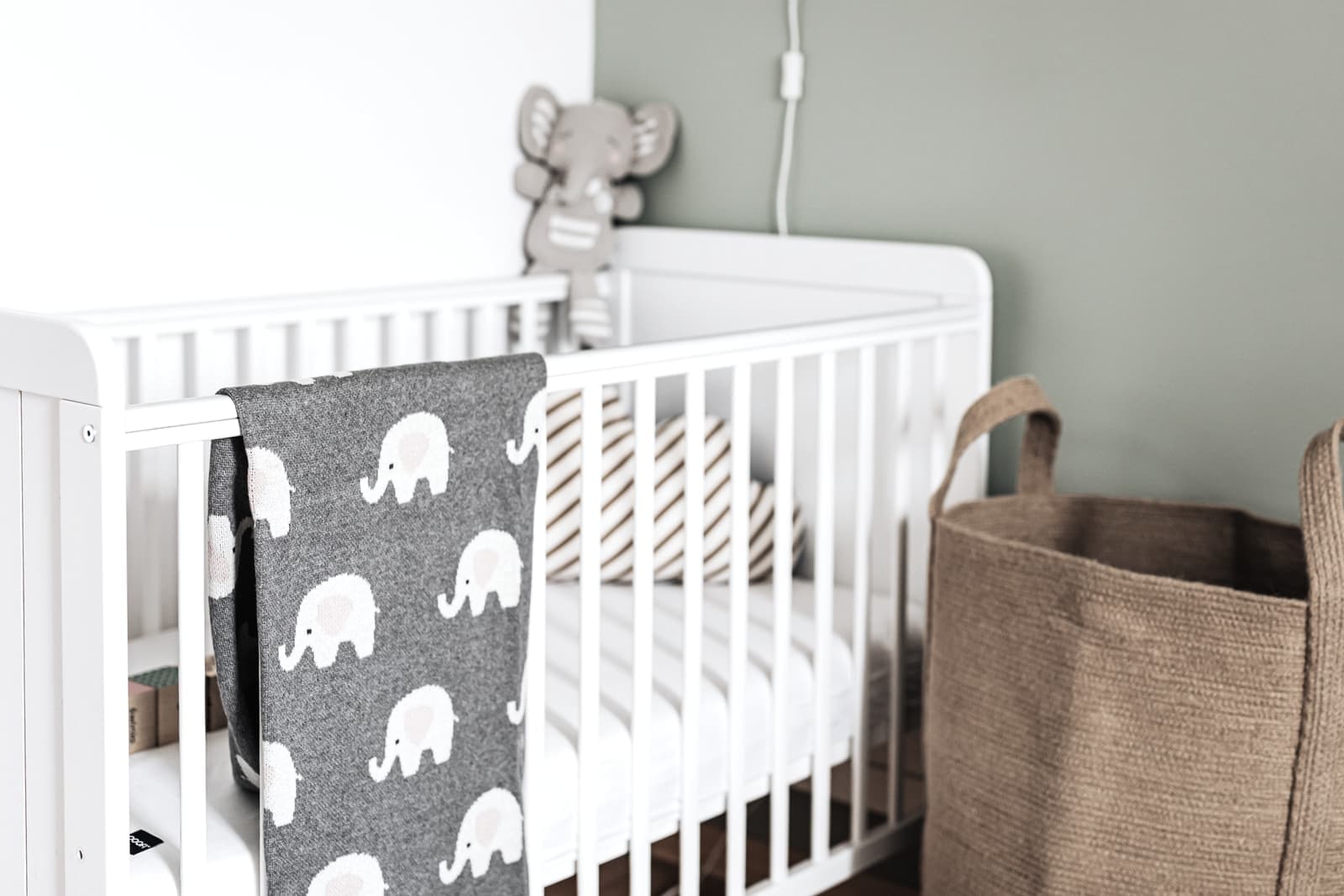 A nursery with a crib and neutral, pale furnishings