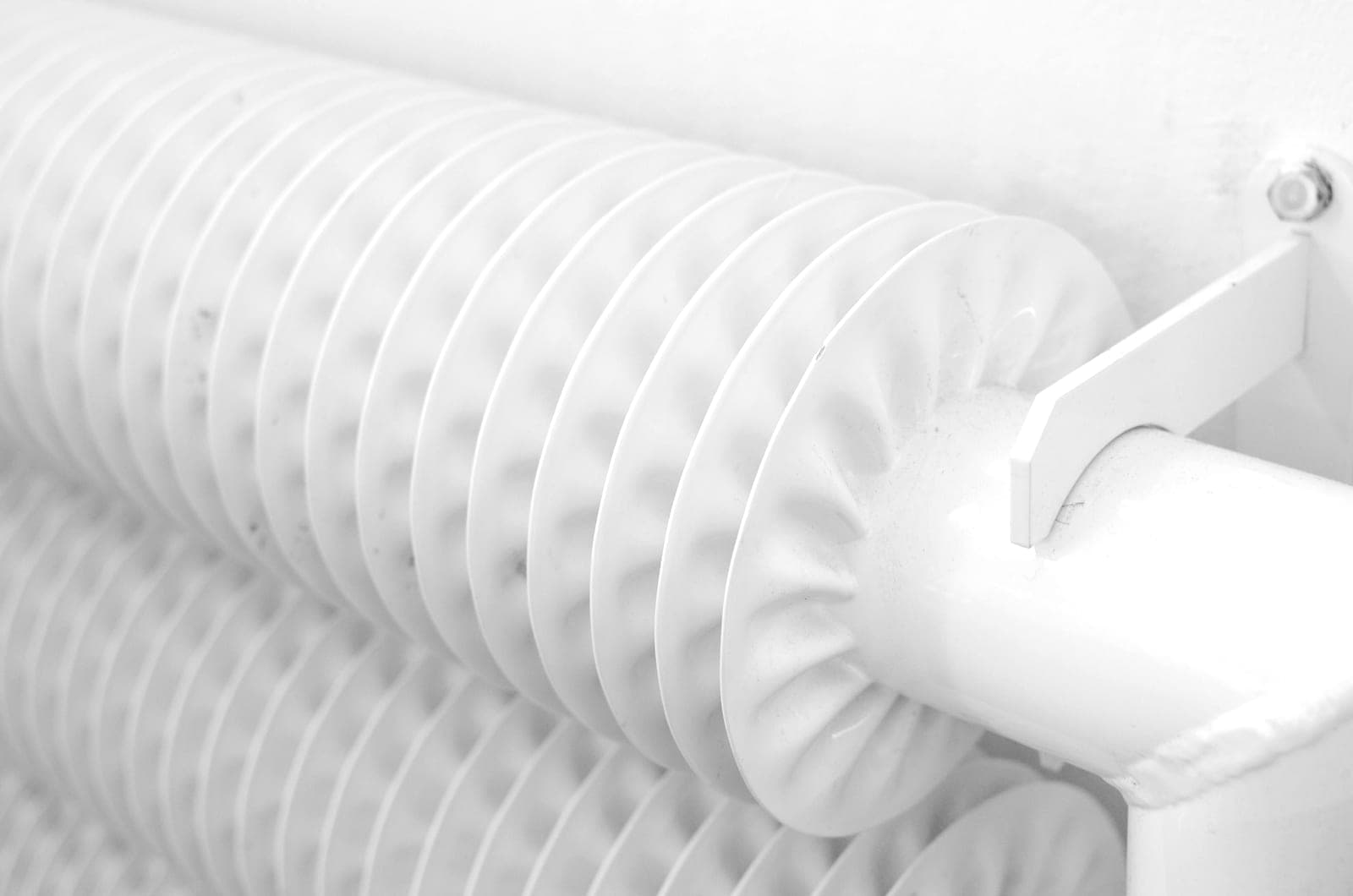 An oil-filled column radiator standing in a pale, uncluttered room