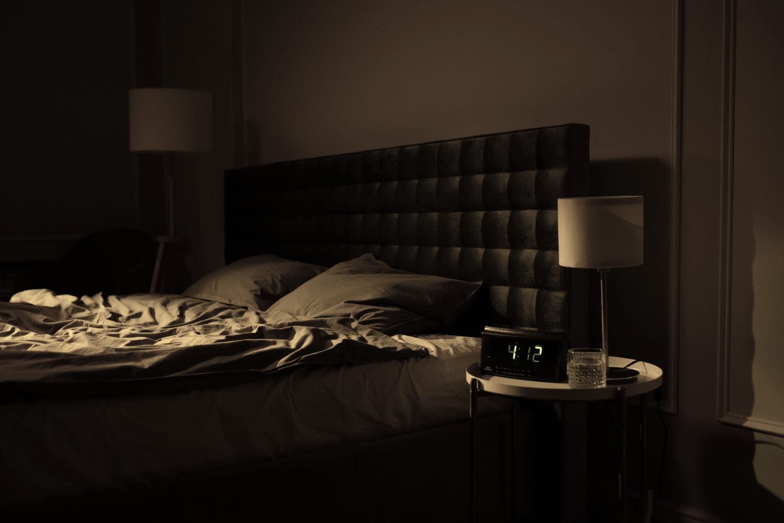 A quiet bedroom at night lit only by a bedside lamp